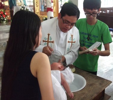 A young husband and wife have their child baptized in a ceremony in Indonesia.